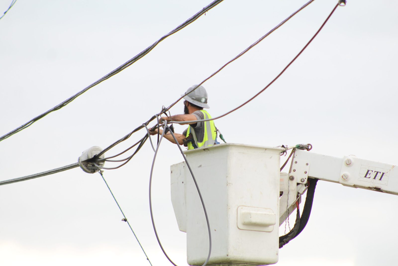 A One World Communications technician working overhead communications lines from an elevated bucket